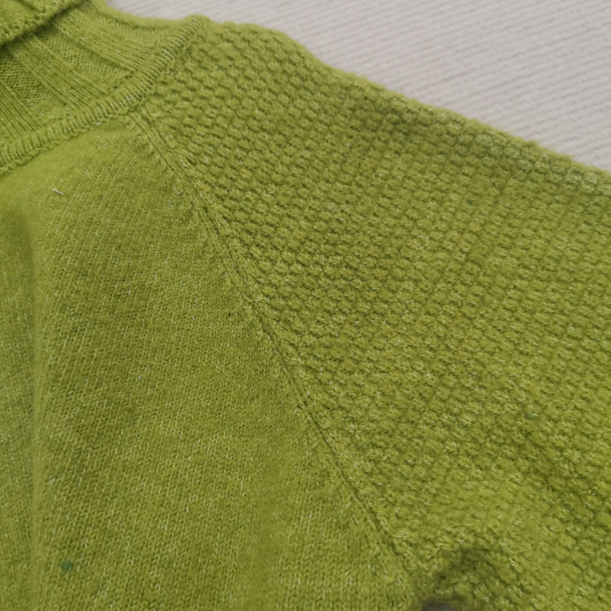 Grüner Strickpullover aus Wolle, Nahaufnahme, Texturdetail, modisch, warm, bequem.